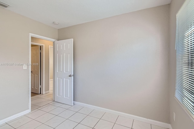 empty room featuring visible vents, baseboards, and light tile patterned floors