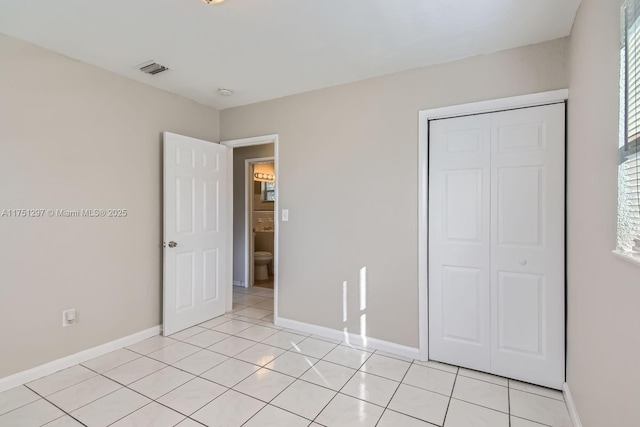 unfurnished bedroom with light tile patterned floors, visible vents, baseboards, and a closet