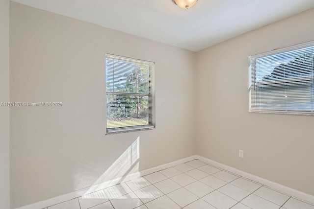 spare room featuring light tile patterned floors and baseboards