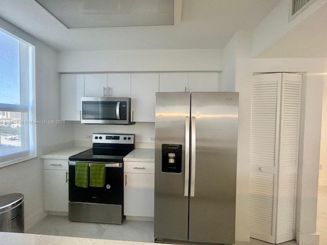 kitchen with stainless steel appliances, white cabinets, light countertops, and visible vents