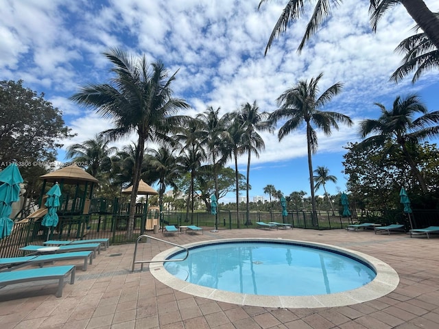 view of swimming pool with playground community and fence