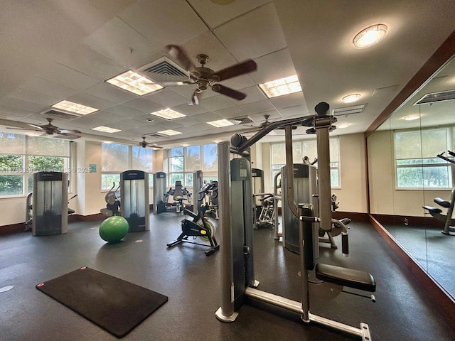 workout area with ceiling fan, visible vents, baseboards, and a drop ceiling