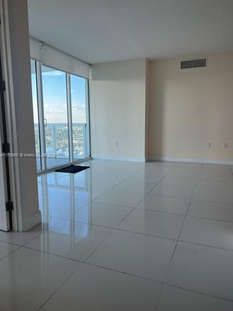 empty room with light tile patterned floors, baseboards, and visible vents