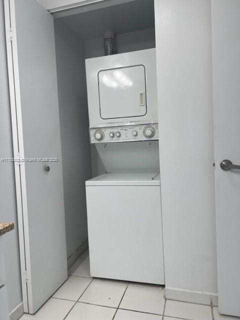 laundry area with stacked washer / drying machine, laundry area, and light tile patterned floors