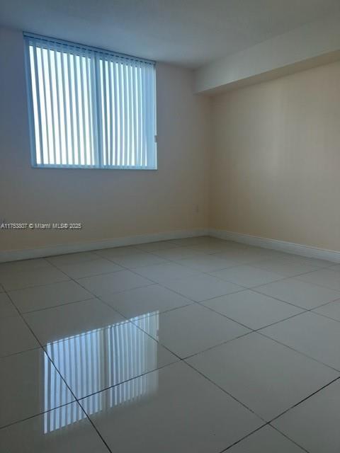 tiled spare room featuring baseboards