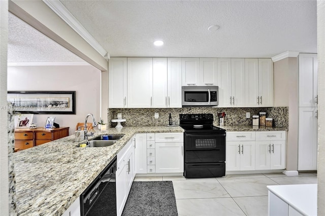 kitchen with black appliances, light stone counters, white cabinets, and a sink