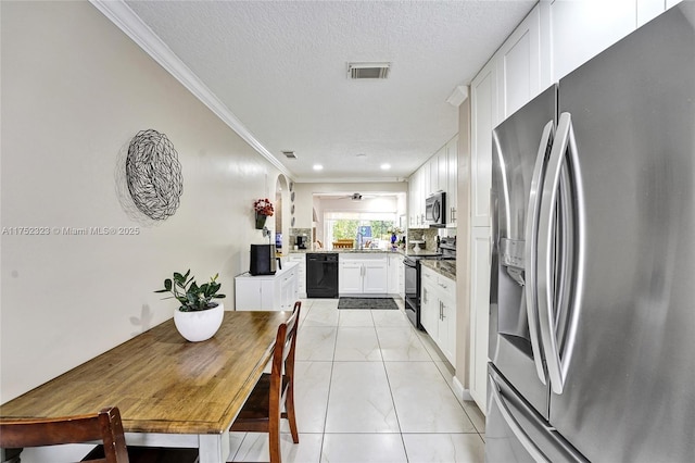 kitchen with light tile patterned floors, a textured ceiling, visible vents, ornamental molding, and black appliances