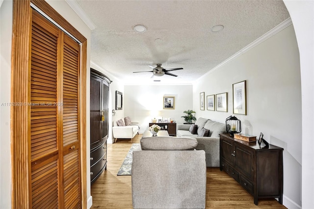 living room featuring crown molding, a textured ceiling, ceiling fan, and wood finished floors