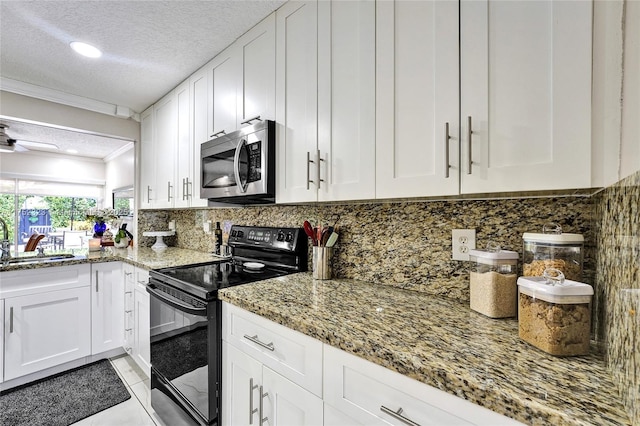 kitchen featuring crown molding, stainless steel microwave, black range with electric stovetop, white cabinetry, and a sink