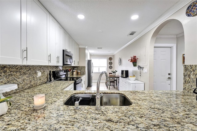 kitchen with appliances with stainless steel finishes, a sink, visible vents, and light stone countertops