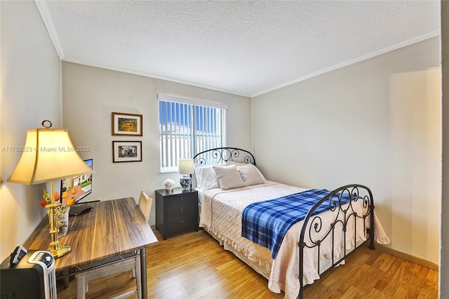 bedroom with baseboards, a textured ceiling, ornamental molding, and wood finished floors