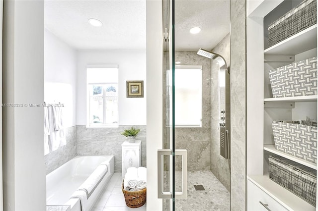 full bath with visible vents, a bath, a textured ceiling, a shower stall, and tile walls