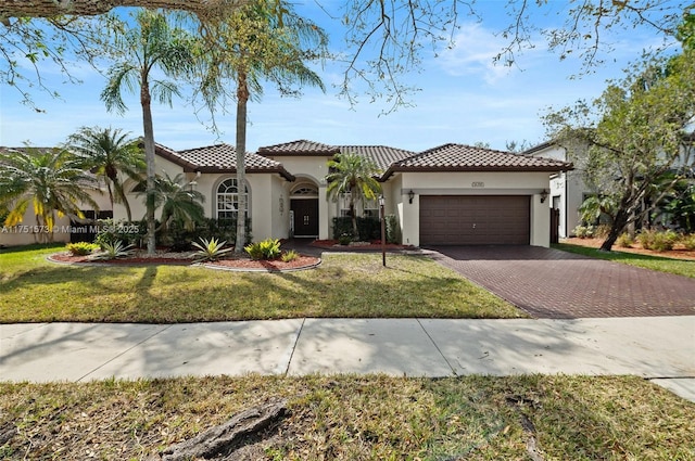 mediterranean / spanish-style home featuring a front lawn, decorative driveway, an attached garage, and stucco siding