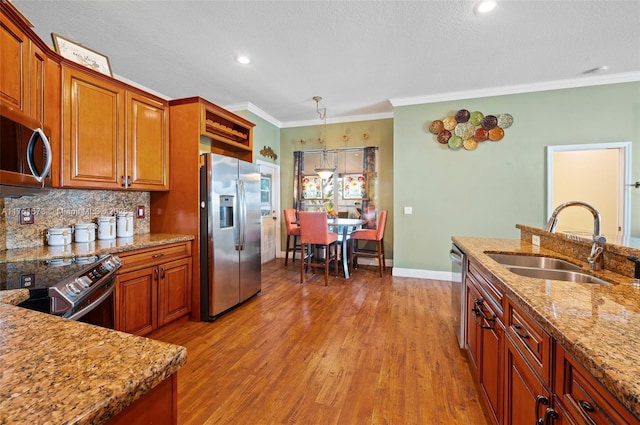 16358 S Mariposa Cir S, Pembroke Pines, FL 33331 - kitchen featuring baseboards, a sink, appliances with stainless steel finishes, brown cabinetry, and wood finished floors