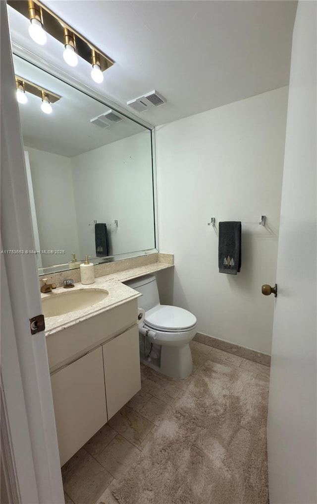 half bath with toilet, vanity, and visible vents