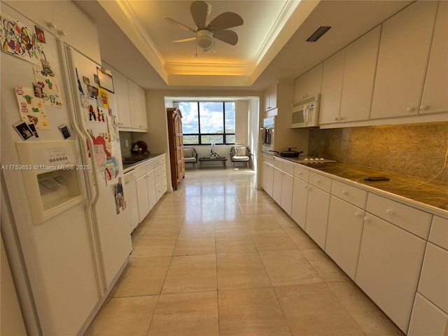 kitchen with a tray ceiling, decorative backsplash, ornamental molding, white cabinets, and white appliances