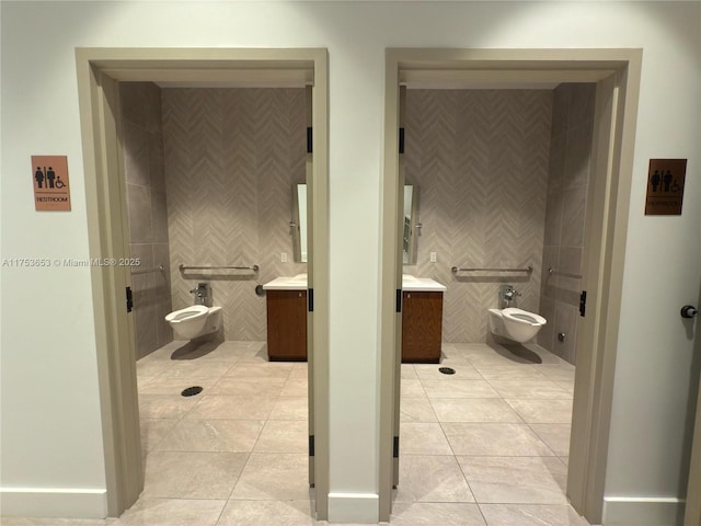 full bath featuring toilet, vanity, tile walls, tile patterned floors, and a bidet