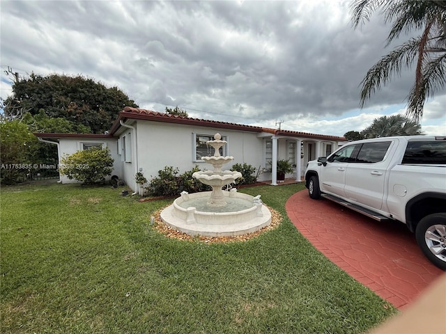 view of front of house with a tiled roof, a front lawn, and stucco siding