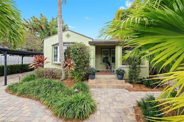 entrance to property featuring fence and stucco siding