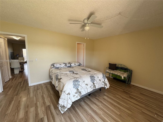 bedroom with a textured ceiling, wood finished floors, and baseboards