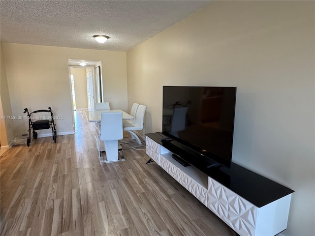 dining area featuring a textured ceiling, baseboards, and wood finished floors