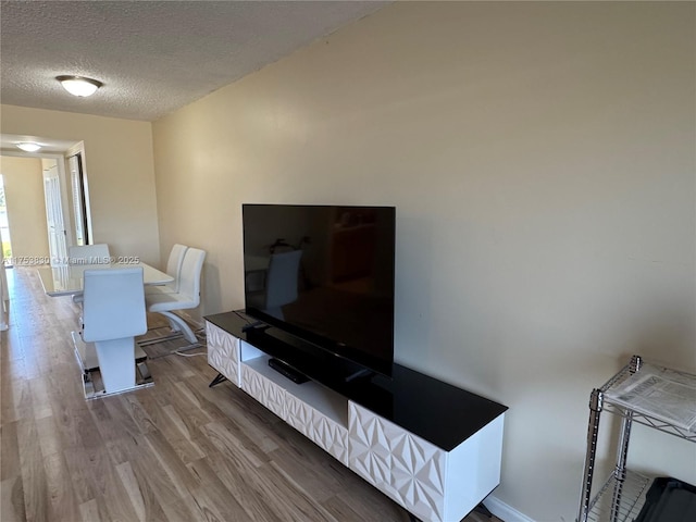 living area with a textured ceiling, baseboards, and wood finished floors