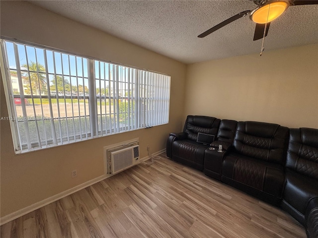 living area with wood finished floors, plenty of natural light, a textured ceiling, and a wall mounted AC