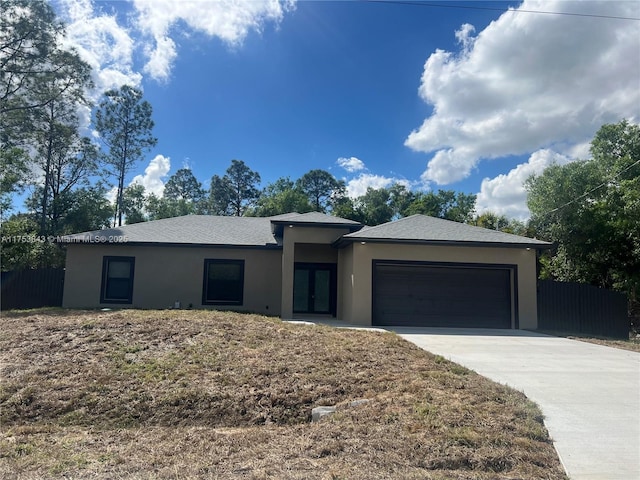 view of front of home with french doors, stucco siding, concrete driveway, fence, and a garage