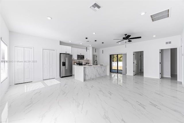 kitchen featuring stainless steel appliances, open floor plan, visible vents, and a center island with sink