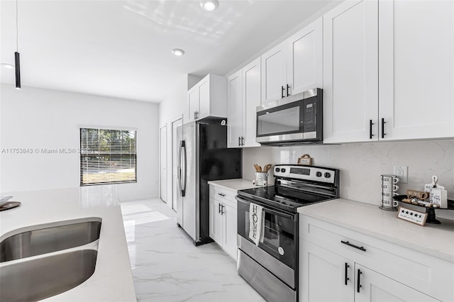 kitchen featuring white cabinets, appliances with stainless steel finishes, marble finish floor, light countertops, and a sink