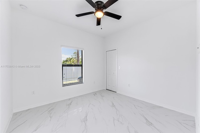 spare room featuring marble finish floor, baseboards, and a ceiling fan