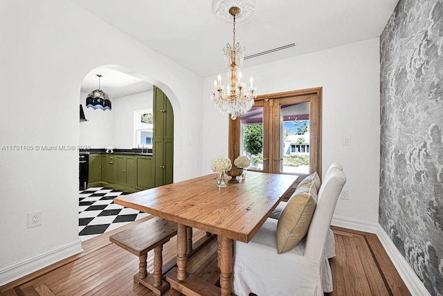 dining room with baseboards, arched walkways, a notable chandelier, and wood finished floors