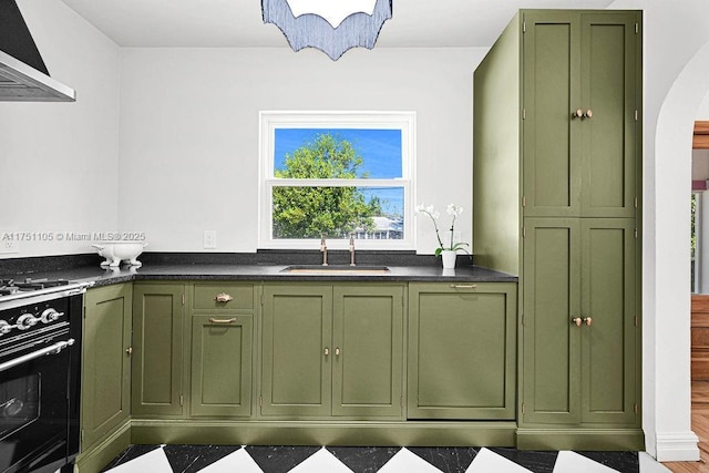 kitchen featuring arched walkways, ventilation hood, a sink, and green cabinetry