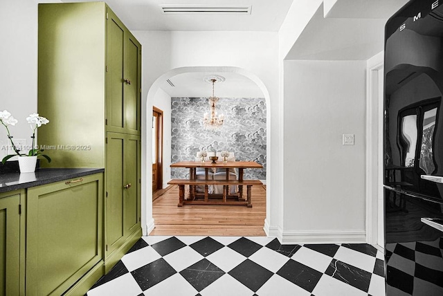 hall featuring arched walkways, a chandelier, visible vents, baseboards, and light floors