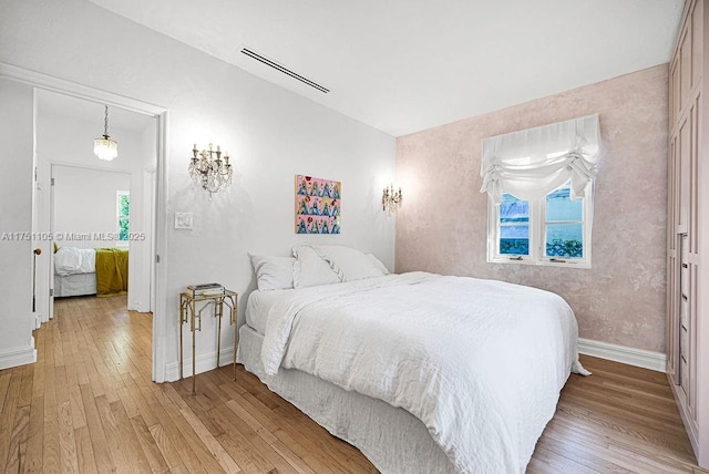 bedroom with multiple windows, light wood-type flooring, visible vents, and baseboards