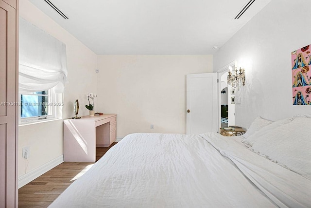 bedroom featuring visible vents, baseboards, and wood finished floors