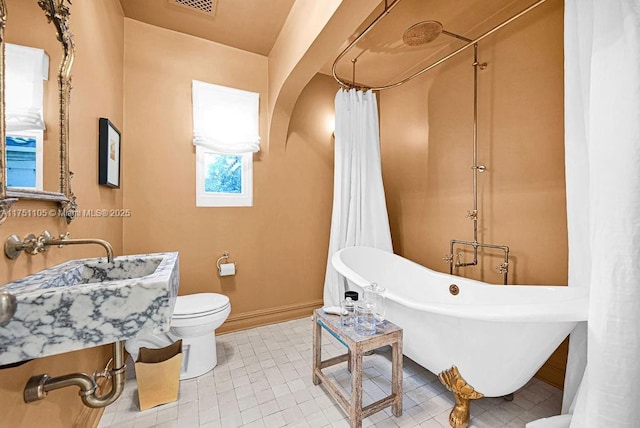 bathroom featuring a soaking tub, visible vents, toilet, baseboards, and tile patterned floors