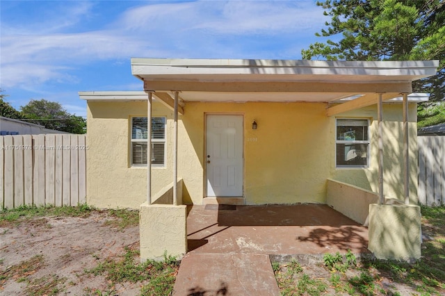 doorway to property with fence and stucco siding