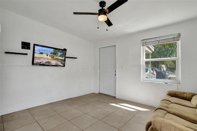 unfurnished living room with light tile patterned floors, ceiling fan, and baseboards