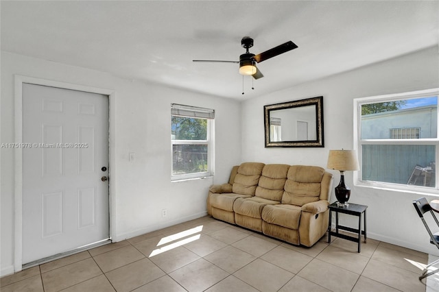 living area featuring a ceiling fan, light tile patterned flooring, and baseboards