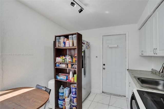 kitchen with marble finish floor, light countertops, white cabinetry, stainless steel refrigerator with ice dispenser, and a sink