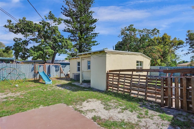 view of home's exterior with central AC unit, fence, a yard, a playground, and stucco siding