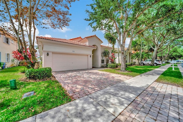 mediterranean / spanish-style home with a front lawn, decorative driveway, an attached garage, and stucco siding