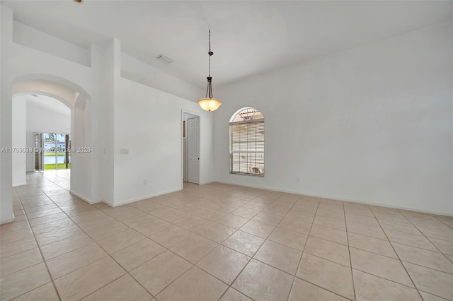 spare room featuring arched walkways, light tile patterned floors, visible vents, and baseboards