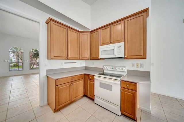 kitchen with light countertops, white appliances, brown cabinetry, and light tile patterned flooring