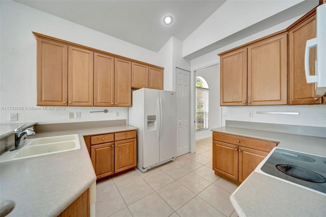 kitchen with light tile patterned floors, light countertops, white appliances, and a sink