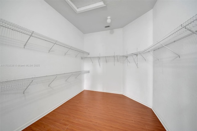 walk in closet featuring attic access and wood finished floors