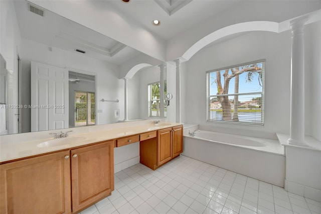 full bath with double vanity, visible vents, a garden tub, ornate columns, and a sink