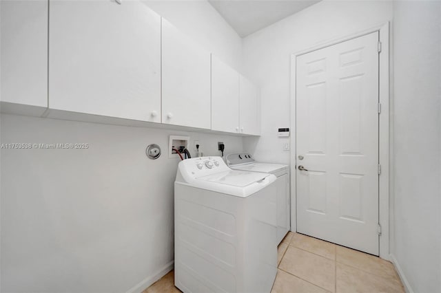 clothes washing area with cabinet space, washer and clothes dryer, baseboards, and light tile patterned floors