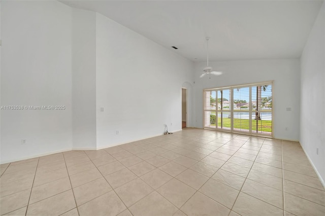 unfurnished room with light tile patterned floors, visible vents, arched walkways, a ceiling fan, and high vaulted ceiling